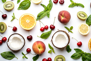 Summer vitamin food concept, various fruit and berries. Peach, kiwi, lemon, cherries, oranges and coconut creative flat lay on white background, top view
