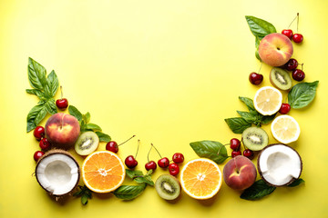 Creative layout made of summer fruits. Food concept. Peach, kiwi, lemon, cherries, oranges and coconut on bright yellow background