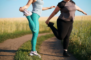 Fit and overweight female friends jogging at outdoor workout. Friendship, motivation, personal trainer, group workout, weight loss, sports and health care