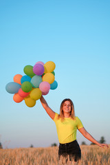 happiness or dream concept, happy woman with multicolored balloons and dandelion at sunset. party, freedom, summertime