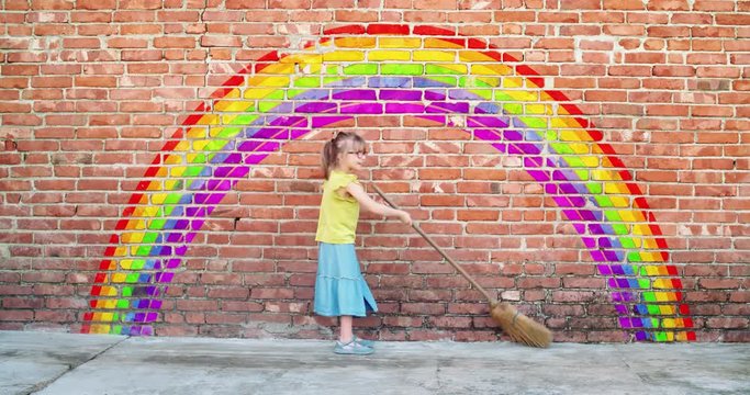 Happy child painting a rainbow on a wall with a broom. Fantasy, imagination, idea,creativity,freedom, love concepts. Lgbt gay pride colorful symbol