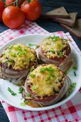 Baked minced cheese with slices of bacon, greens. Dark wooden background.
