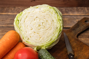 Cutting a head of white cabbage with vegetables on a cutting board. Ingredients for Salad