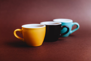 Threee colorfull cups of espresso coffee on dark background