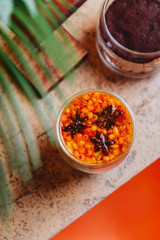 Sea buckthorn tea with orange in a glass cups with fresh sea buckthorn berries and leaves. Herbal vitamin tea.