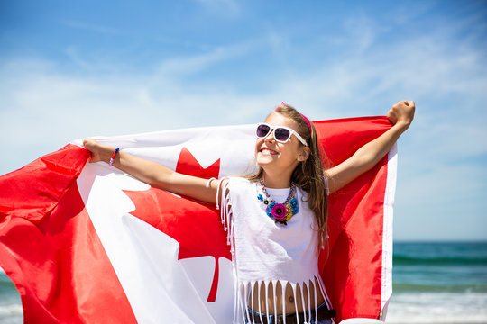Happy girl carries Canadian flag on Canada Day, July 1