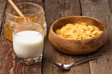 Cornflakes in a wooden plate. Breakfast of cereal with honey and milk. Quick breakfast with cornflakes