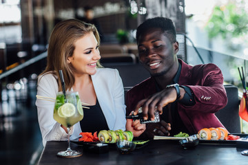 Portrait of happy  couple having fun while eating sushi rolls in restaurant in modern terrace.