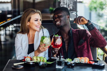 Eating sushi together. Beautiful couple eating sushi while sitting close to each other on the restaurant.