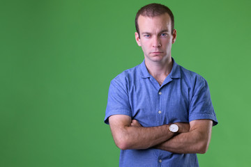 Portrait of businessman with arms crossed against green background