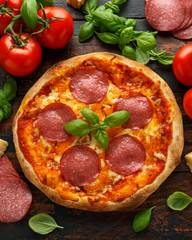 Homemade Pepperoni, Salami Pizza with basil, tomatoes, cheese on wooden table. ready to eat