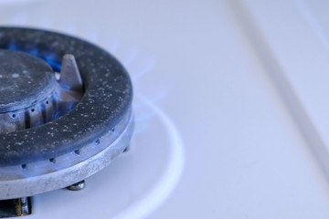 Gas burning from a kitchen gas stove in big gas burner. Half of gas burner in left side. Close-up...