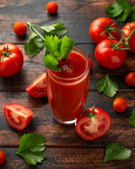 Tomato juice in glass with celery on rustic wooden table