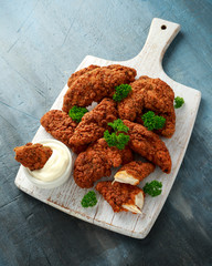 Breaded chicken strips with mayonnaise on white wooden board