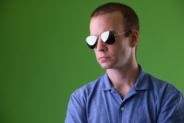 Face of businessman wearing sunglasses against green background - Powered by Adobe