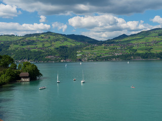 Fototapeta na wymiar Spiez, Switzerland - May 30th 2019: People are sailing sailboat at Thun Lake, Spiez Switzerland