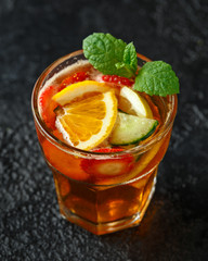 Refreshing Pimms Cocktail with Fruit and vegetables on rustic black table
