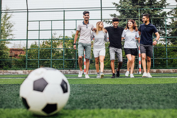 Happy friends  preparing kicking football on the sports field during soccer match..