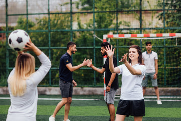Group of multiethnic friends playing soccer on the field - Football match. Relaxing together.