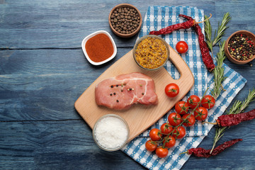 Raw pork steak on the board, meat and ingredients for cooking, spices herbs and vegetables on a light background. top view