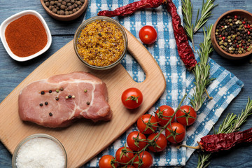 Raw pork steak on the board, meat and ingredients for cooking, spices herbs and vegetables on a light background. top view