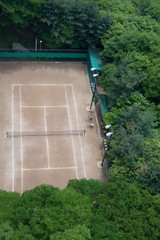tennis court of a green forest seen from above.