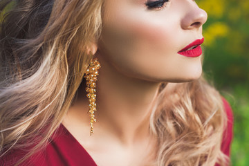 Close up of woman face with red lips and fashion gold earrings