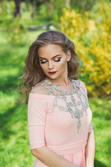 Beautiful woman with body jewelry in pink dress with red lips and make up outside