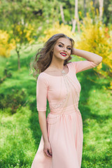 Beautiful woman with body jewelry in pink dress with red lips and make up outside