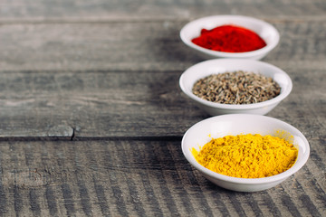 Spices in little white bowls on brown wooden background. Indian spice. Top view with space for text, copy space
