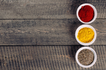 Spices in little white bowls on brown wooden background. Indian spice. Top view with space for text, copy space