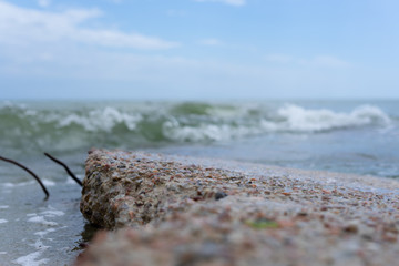 Concrete slab with protruding rusty reinforcement on the beach. Waves run onto the shore.