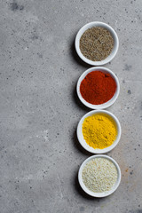 Spices in little white bowls on gray stone concrete background. Indian spice. Top view with space for text, copy space