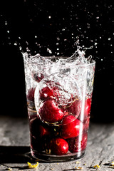 Splash of cherries dropped in a glass of water. Close up macro in studio for wallpaper.