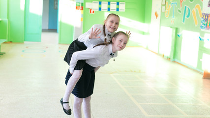 Fototapeta na wymiar School friends at recess A tall girl rolls her friend in her lap.