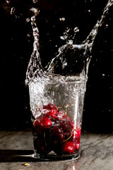 Splash of cherries dropped in a glass of water. Close up macro in studio for wallpaper.