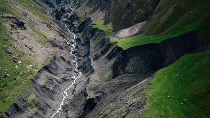 Aerial view of river in mountains of Georgia. Nature, fields, green grass, stones, hills.