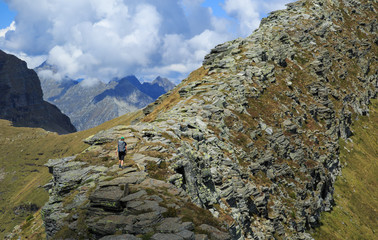 A hiker on a narrow ridge in the mountains. Via Alta Verzasca, Switzerland.