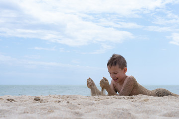 A boy of 9 years old is bathing and resting on a sandy beach by the sea.