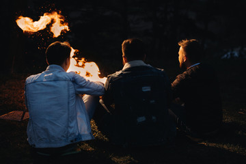 Friends hanging out near the flaming barbecue grill at the sunset