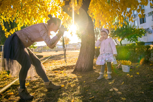 Girl with mom in autumn. Mom takes a picture of her daughter. Autumn photo shoot child. Mother photographer. Mother with her little daughter in the autumn park on a walk. 