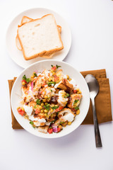 Bread chaat/chat is a yummy starter/appetizer from India, served in a bowl garnished with tomato, sev and coriander and masala. selective focus