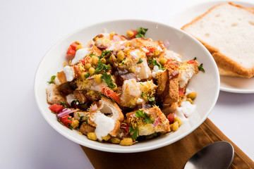 Bread chaat/chat is a yummy starter/appetizer from India, served in a bowl garnished with tomato, sev and coriander and masala. selective focus