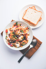 Bread chaat/chat is a yummy starter/appetizer from India, served in a bowl garnished with tomato, sev and coriander and masala. selective focus