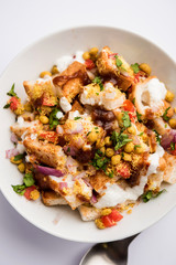 Bread chaat/chat is a yummy starter/appetizer from India, served in a bowl garnished with tomato, sev and coriander and masala. selective focus