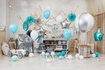 A large number of color balloons. Birthday teal and silver decorations with gifts, toys, garlands and balloon for yearling little baby party on a white playroom background.