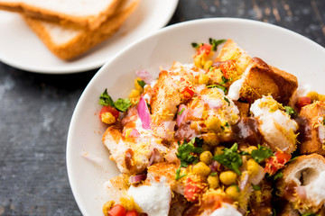 Bread chaat/chat is a yummy starter/appetizer from India, served in a bowl garnished with tomato, sev and coriander and masala. selective focus