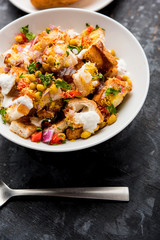 Bread chaat/chat is a yummy starter/appetizer from India, served in a bowl garnished with tomato, sev and coriander and masala. selective focus
