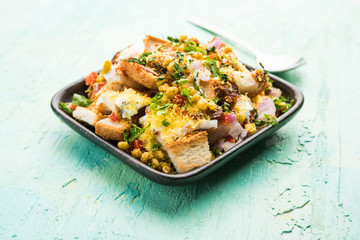 Bread chaat/chat is a yummy starter/appetizer from India, served in a bowl garnished with tomato, sev and coriander and masala. selective focus