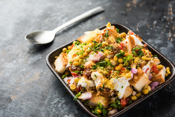 Bread chaat/chat is a yummy starter/appetizer from India, served in a bowl garnished with tomato, sev and coriander and masala. selective focus